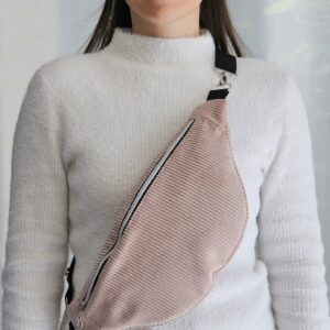 Femme portant un sac banane en velours côtelé rose poudré en bandoulière