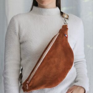 Femme portant un sac banane en velours côtelé terracotta en bandoulière
