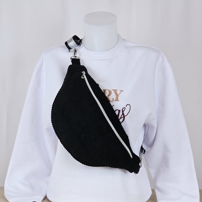Banane-velours-noir-brode-personnalise.jpg Sac banane en velours noir personnalisé avec broderie, présenté sur un mannequin avec un sweat blanc