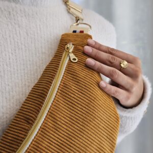 Sac banane en velours côtelé couleur moutarde avec fermeture dorée porté sur un pull blanc