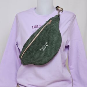 Sac banane en velours côtelé vert sauge personnalisé présenté sur un mannequin avec un sweat mauve