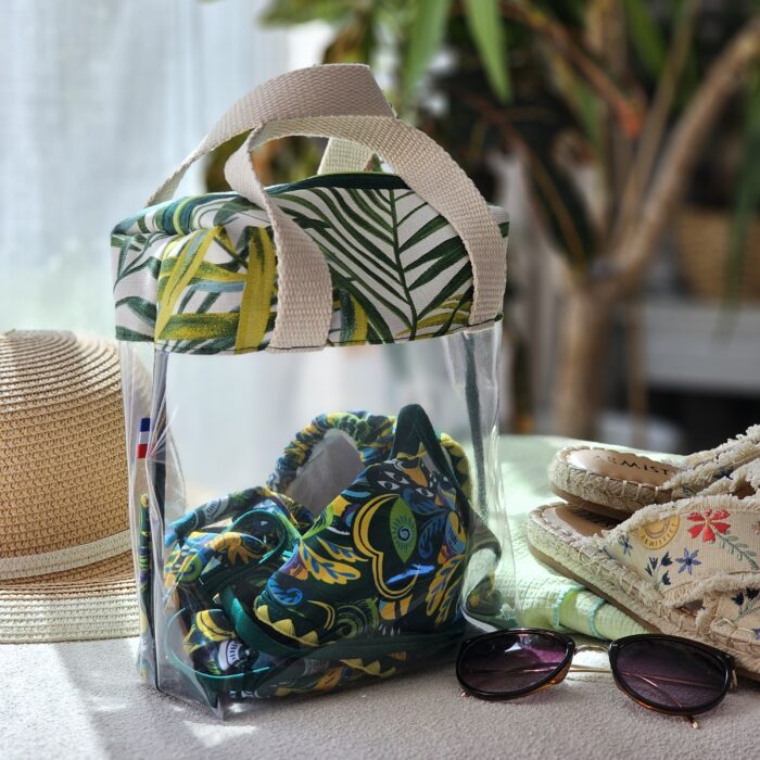 sac-maillot-transparent-tropical-ambiance-plage.jpg Sac à maillot de bain transparent avec tissu tropical à feuilles vertes dans une ambiance plage et vacances