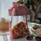 Sac à maillot de bain transparent avec tissu liberty rouge dans une ambiance plage estivale