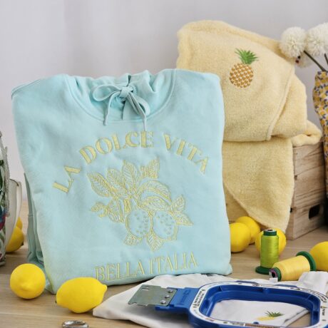 Sweat bleu brodé La Dolce Vita Bella Italia avec motif citron présenté dans un atelier de broderie