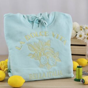 Sweat bleu brodé La Dolce Vita Bella Italia avec motif citron présenté dans un atelier de broderie